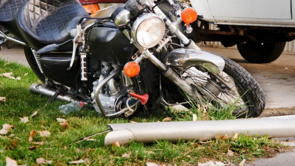 A black cruiser motorcycle lying on its side on a grassy curb after a crash